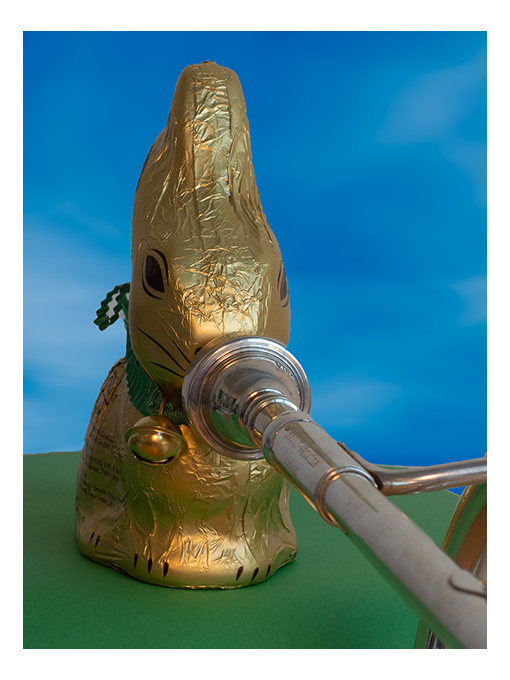 gold wrapped chocolate rabbit playing a cornet, close up on face